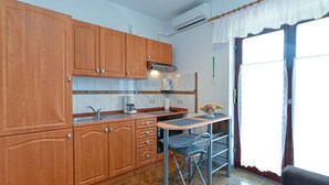 A kitchen with wooden cabinets, a coffee maker, and a dining area with a table and chairs. - Holiday apartment with air conditioning and barbecue facilities (Poreč)