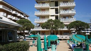 A multi-story hotel with balconies, outdoor seating, and trees. - Holiday apartment (Lido di Jesolo)