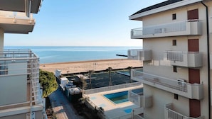 A high-rise building with balconies overlooking a beach and a swimming pool. - Holiday apartment (Lido di Jesolo)
