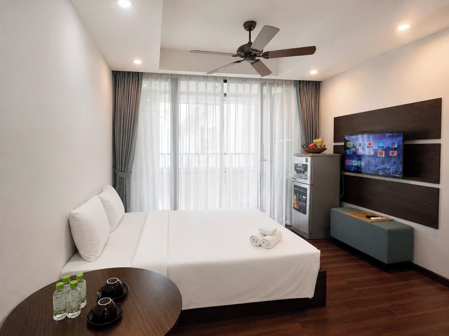 Habitación de hotel con cama, escritorio con artículos de aseo, televisión y minibar.