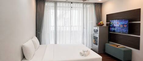 Habitación de hotel con cama, escritorio con artículos de aseo, televisión y minibar.