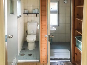 Une petite salle de bain comprenant des toilettes, un lavabo et une petite fenêtre.