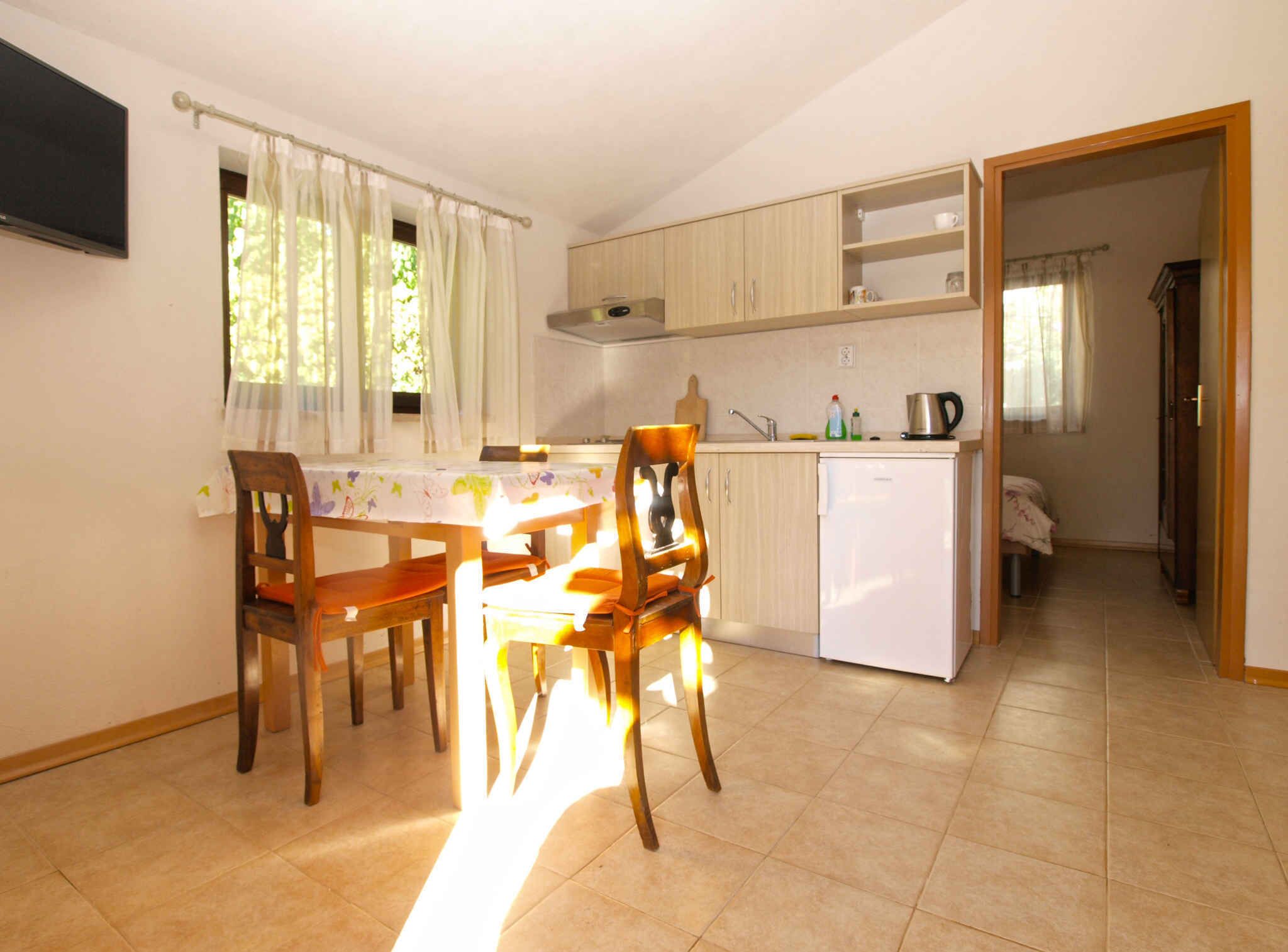 A compact kitchen with a dining area, a refrigerator, and a TV mounted on the wall.