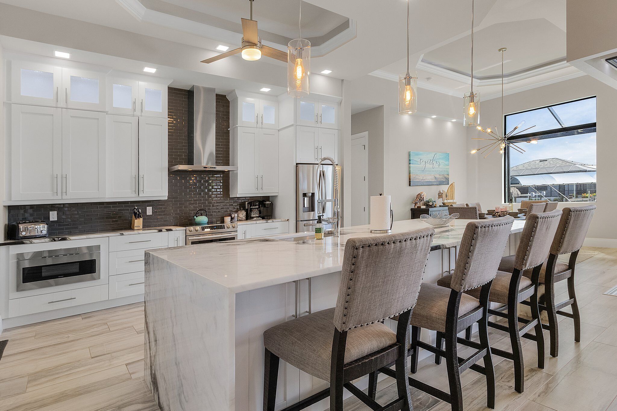 A modern kitchen with white cabinets, a large island, and bar stools.