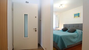 A bedroom with a bed, a door, and a wall-mounted light fixture. - Holiday apartment with air conditioning (Fažana)