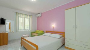 A bedroom with a bed, a wardrobe, a desk, a chair, a television, and a window with curtains. - Holiday apartment with air conditioning (Novigrad)