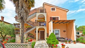 A two-story house with a stone facade, a balcony with potted plants, and a tiled entrance. - Holiday apartment with air conditioning (Novigrad)