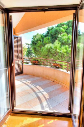 A balcony with a view of green trees and a railing.