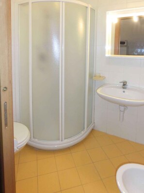 Ein Badezimmer mit einer Duschkabine, einem Waschbecken und einer Toilette.