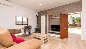A modern living room with a sofa, coffee table, TV, and fireplace. - CASA ROJA - Lovely villa with private pool (Vejer de la Frontera)