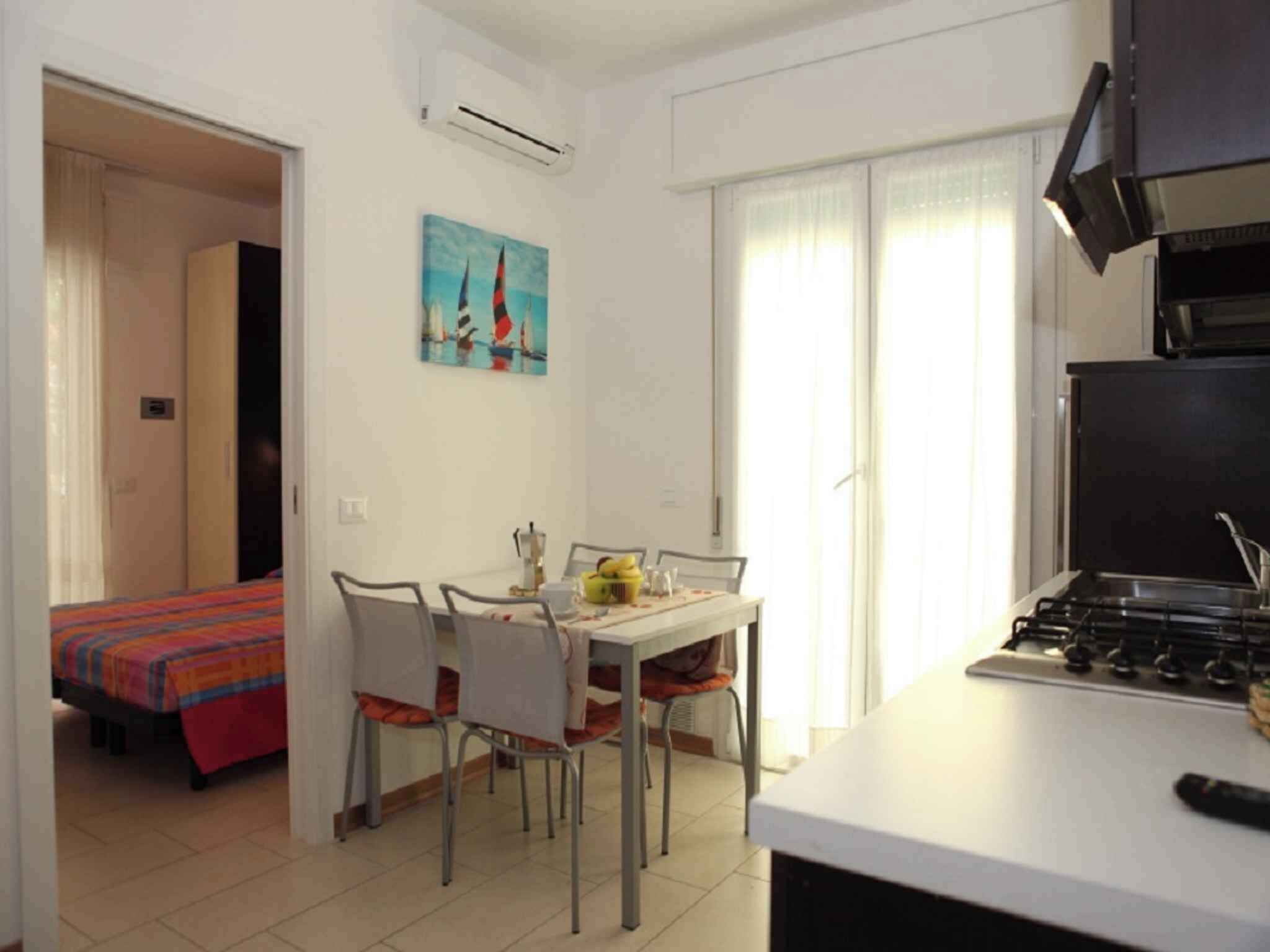 Una cocina compacta con comedor, una cama con colcha colorida y un cuadro en la pared.