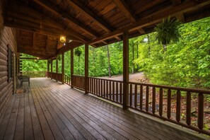 Eine Holzterrasse mit Geländer, Bänken und Blick auf einen Wald.
