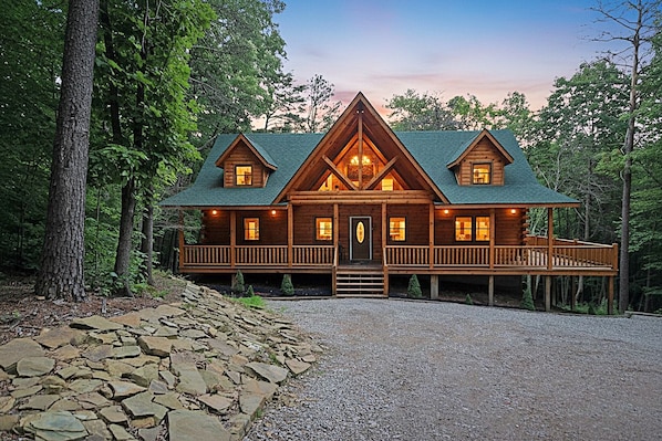Una baita di legno con un portico, diverse finestre e un vialetto in pietra che conduce all'ingresso.