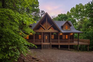 A log cabin with a porch, a front door, and a small deck. - Grand Valley Lodge, 8-Bedrm Lodge - Hocking Hills (South Bloomingville)