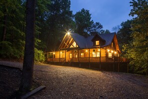 Eine Holzhütte mit Veranda, umgeben von Bäumen.