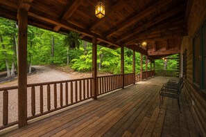 A wooden deck with a railing, benches, and a view of a forested area. - Grand Valley Lodge, 8-Bedrm  Lodge - Hocking Hills (South Bloomingville)
