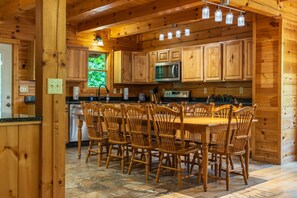 A wooden cabin-style kitchen with a central island, wooden chairs, and a built-in microwave. - Grand Valley Lodge, 8-Bedrm  Lodge - Hocking Hills (South Bloomingville)