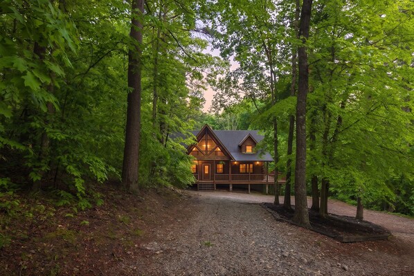 A cabin with a porch, surrounded by trees.