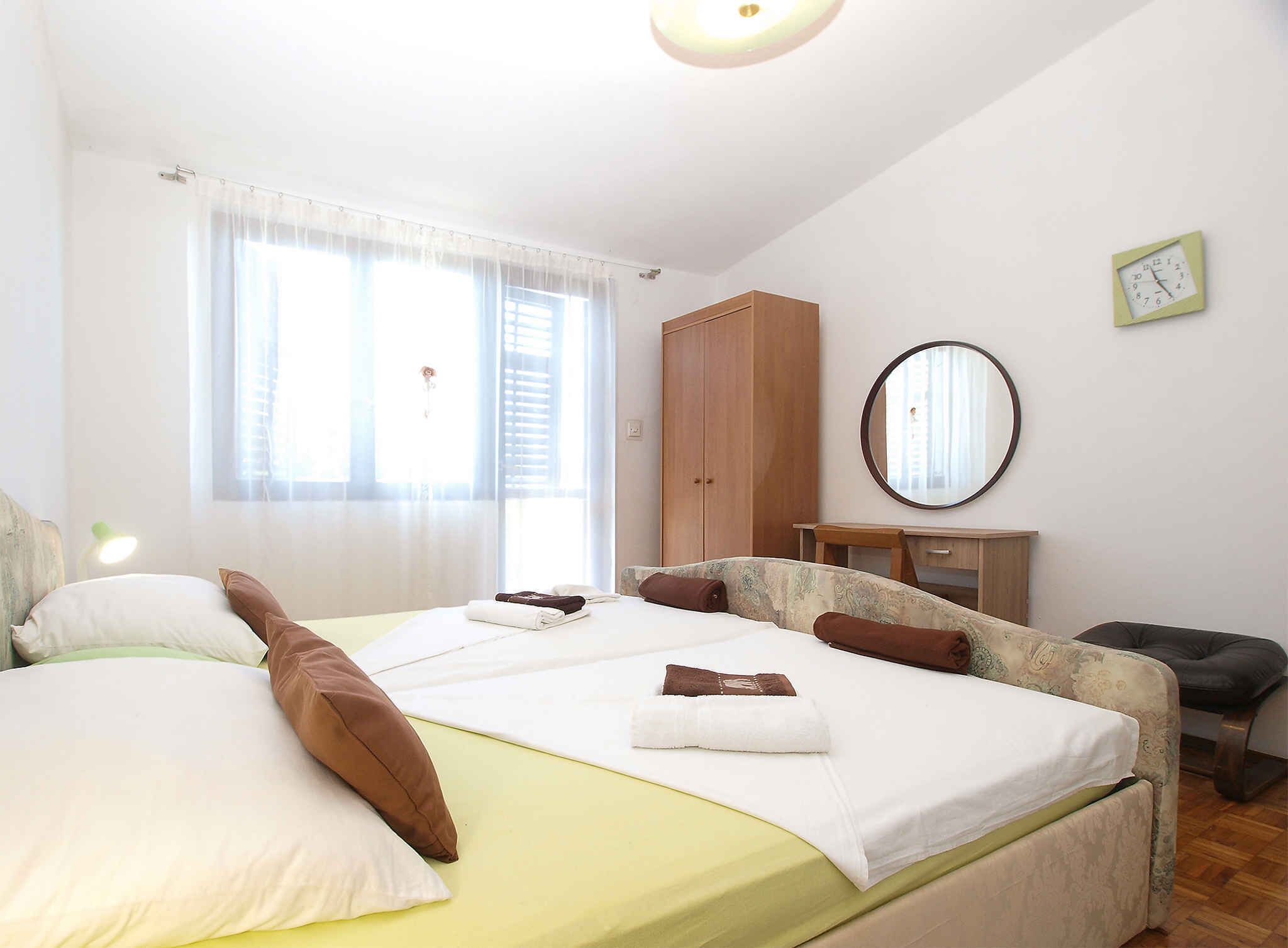 Een goed verlichte slaapkamer met een bed, een kledingkast, een spiegel en een raam met gordijnen.