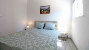 A bedroom with a bed, a painting on the wall, and a small table with a lamp. - Holiday apartment with air conditioning (Fažana)