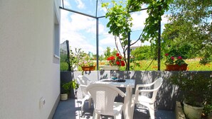 A patio with a table and chairs, surrounded by potted plants and flowers. - Holiday apartment with air conditioning (Fažana)