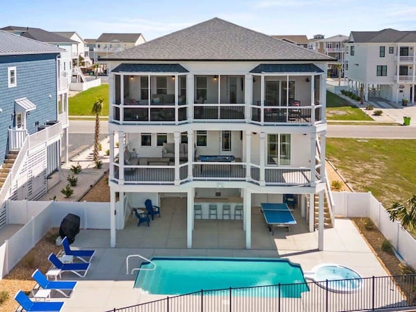 A multi-story residential building with a balcony, a pool, and outdoor seating.