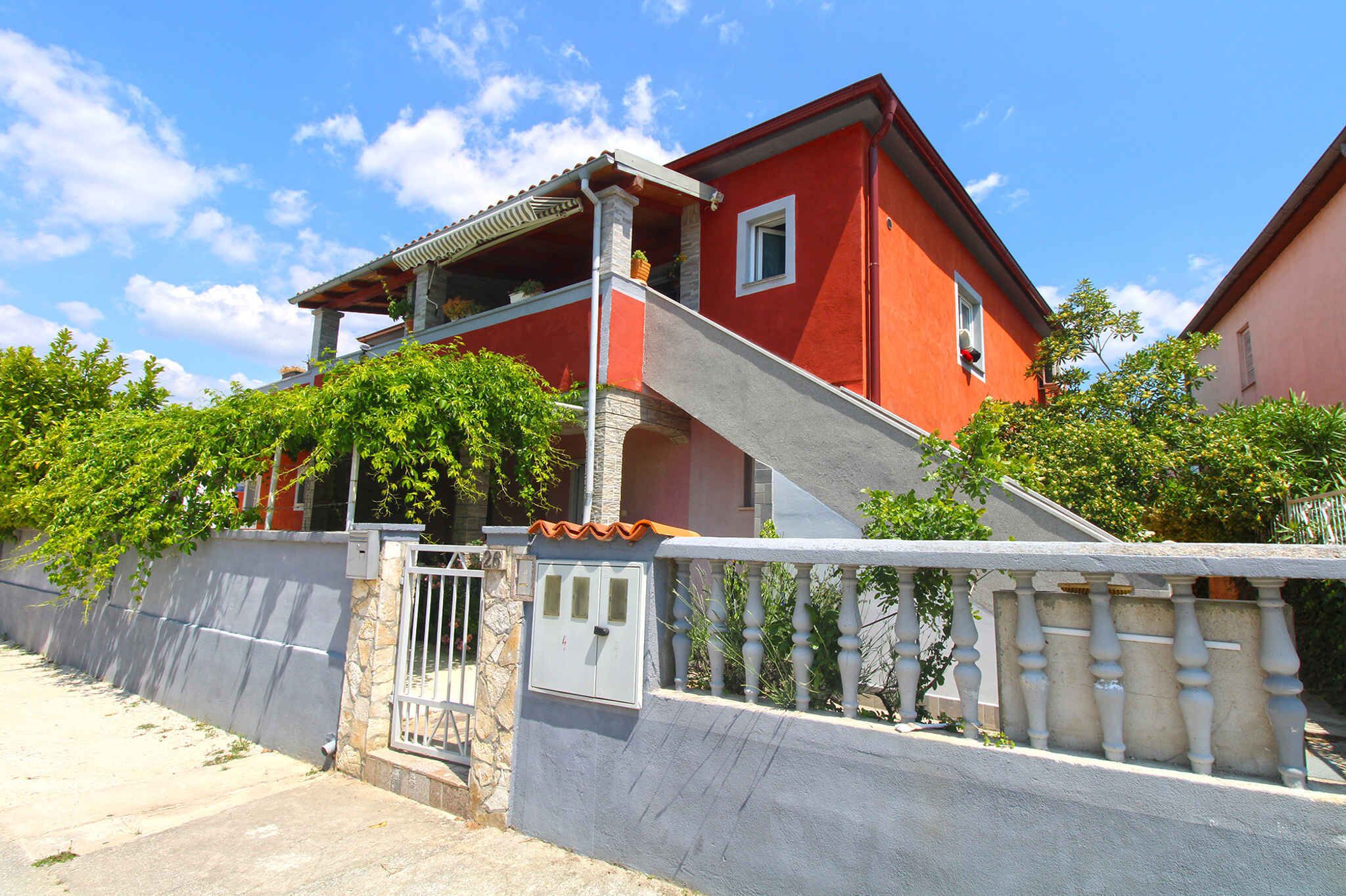 Ein zweistöckiges Haus mit roter Fassade, einem Balkon und einem verschlossenen Eingang.
