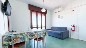 Una habitación con una mesa de comedor, sillas, un sofá, un televisor y un extintor.