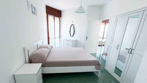 Un dormitorio con cama, mesita de noche, armario e iluminación colgante.