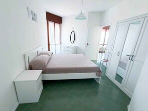 Un dormitorio con cama, mesita de noche, armario e iluminación colgante.