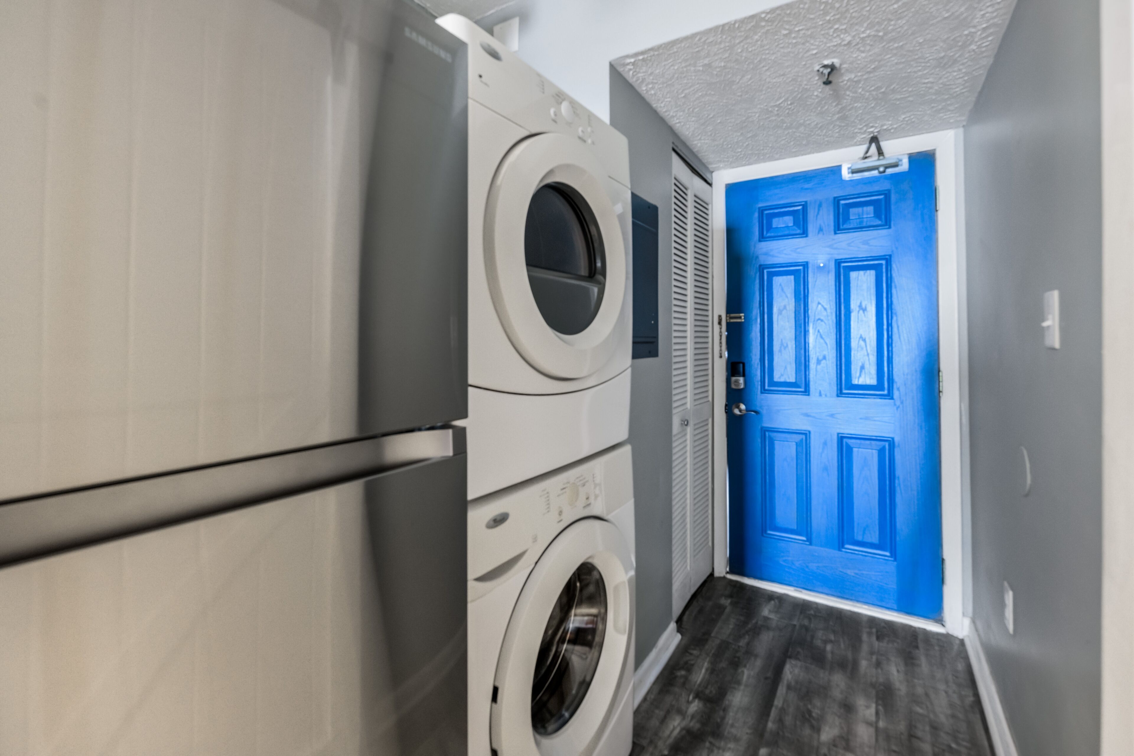 Un cuarto de lavandería con una puerta azul y una lavadora blanca.