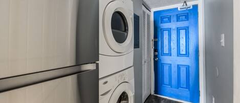 Un cuarto de lavandería con una puerta azul y una lavadora blanca.