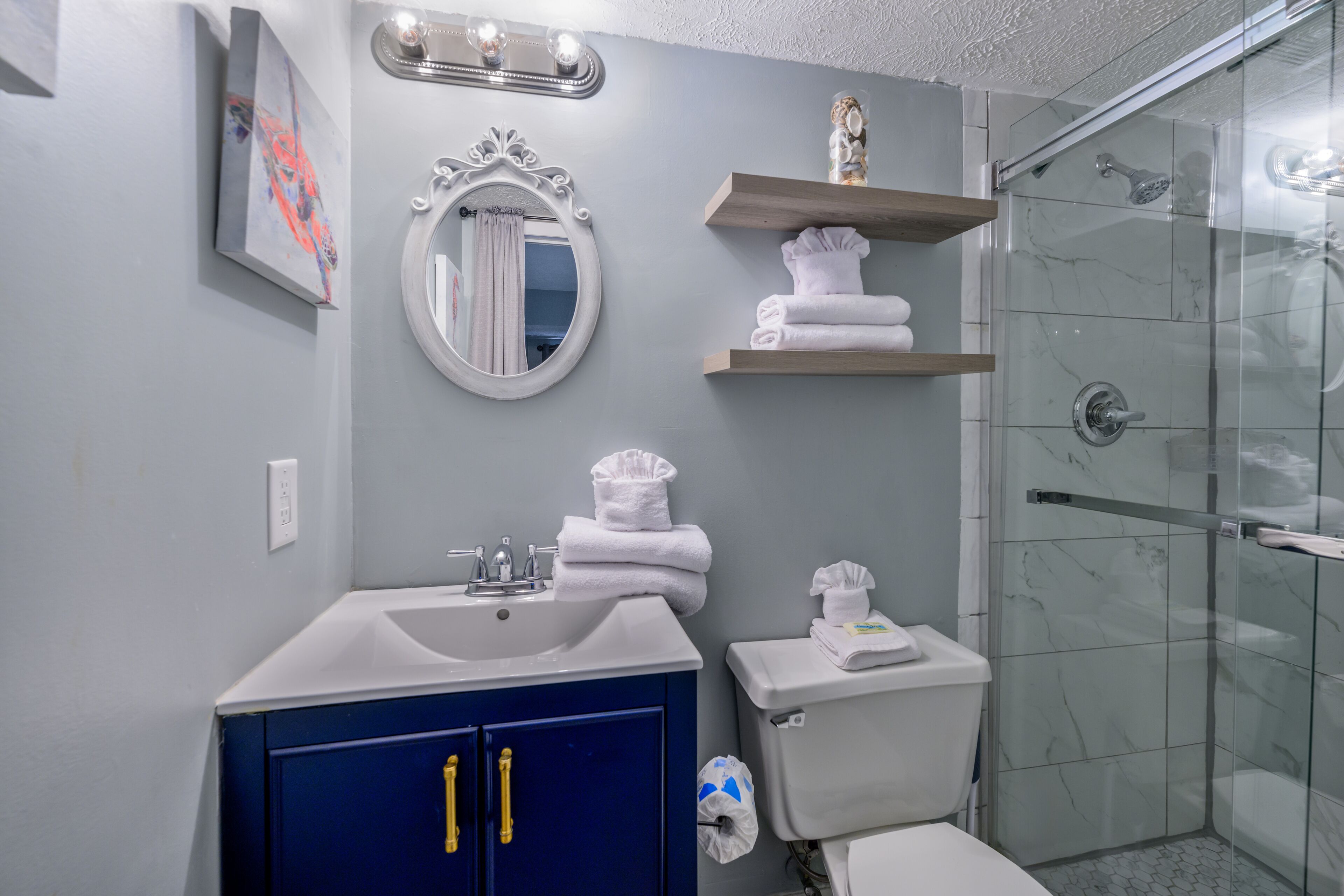 A bathroom with a sink, mirror, toilet, and shower.