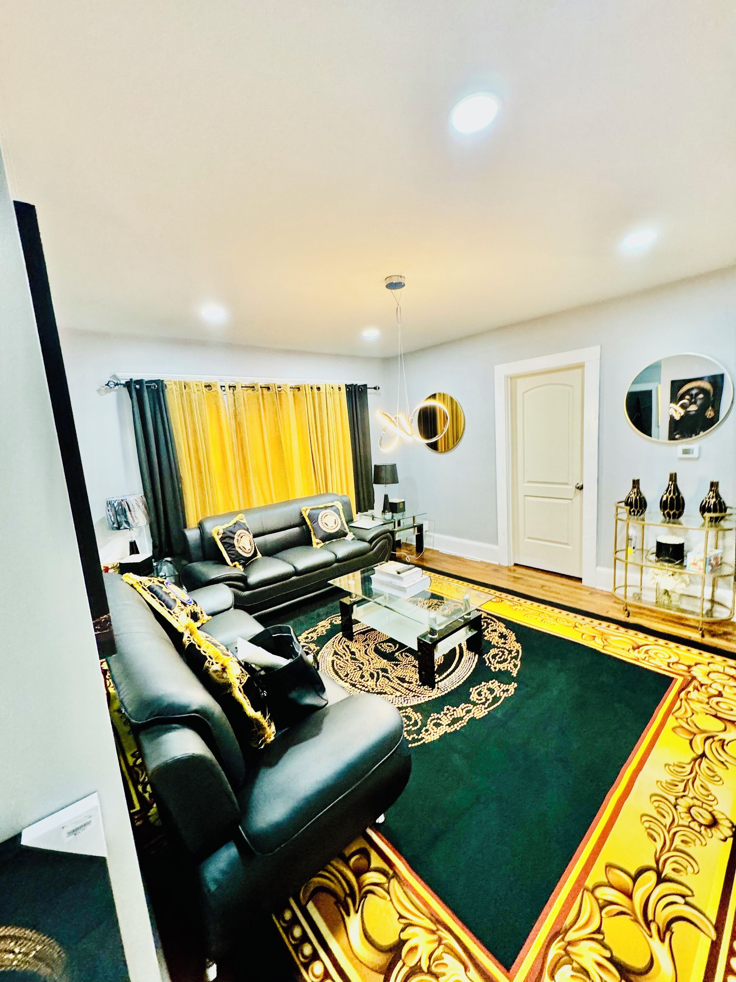 A living room with a black sofa, a coffee table, and a patterned rug.