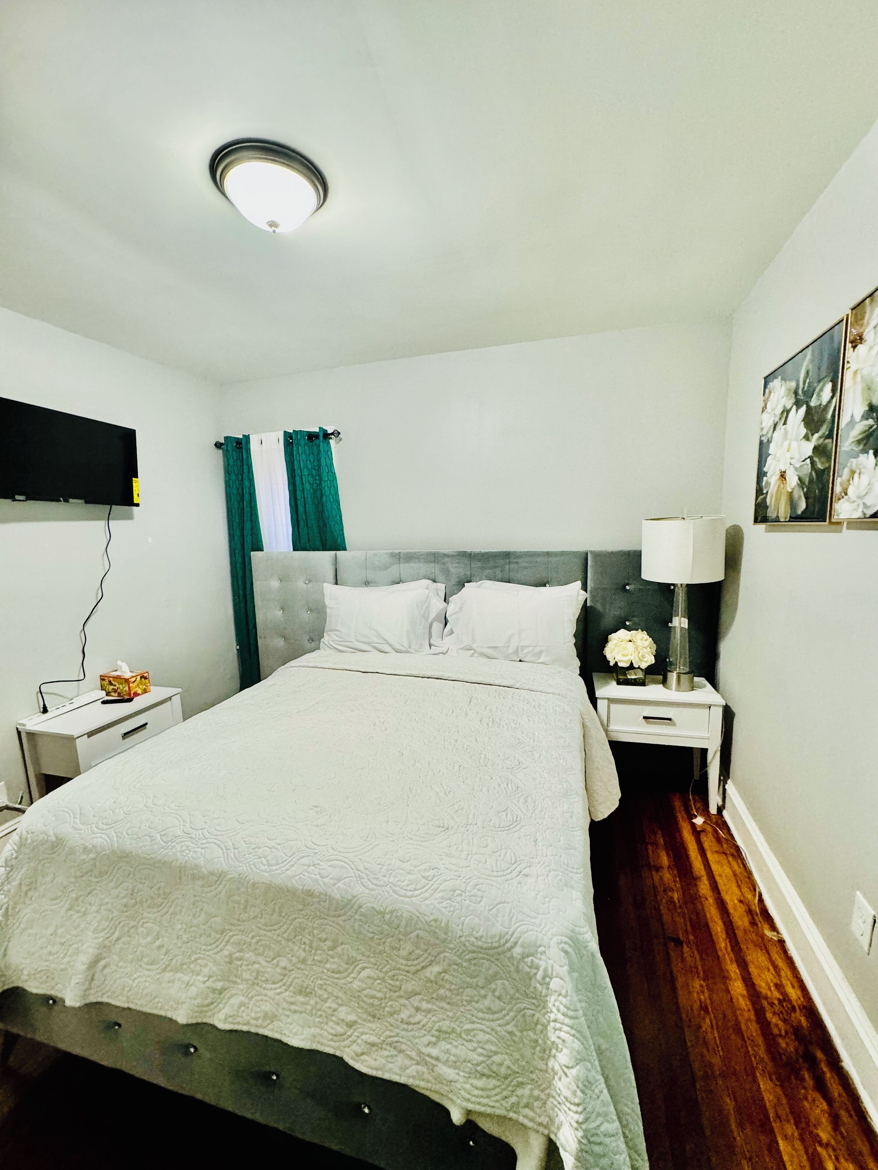 Une chambre à coucher bien rangée, avec un lit, des tables de chevet, une lampe et un tableau au mur.