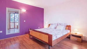 A bedroom with a wooden bed, a nightstand, and a window with a view of trees. - Holiday apartment with air conditioning (Valbandon)