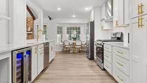 Una cocina moderna con armarios blancos, detalles dorados y una isla central con sillas.