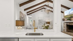 Una cocina con encimera blanca, grifo dorado y lavavajillas integrado.