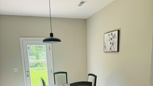 A dining area with a table, chairs, a pendant light, and a door leading to a garden. - Brand NEW Entire home in Statesville, NC (Statesville)