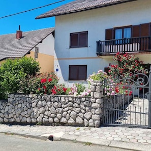 Uma casa de dois andares com parede de pedra, varanda e portão.