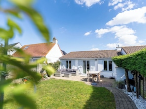 A house with a tiled roof, a covered patio, and a lawn. - Lovely apartment in villa for 4 guests with WIFI and TV (De Haan)
