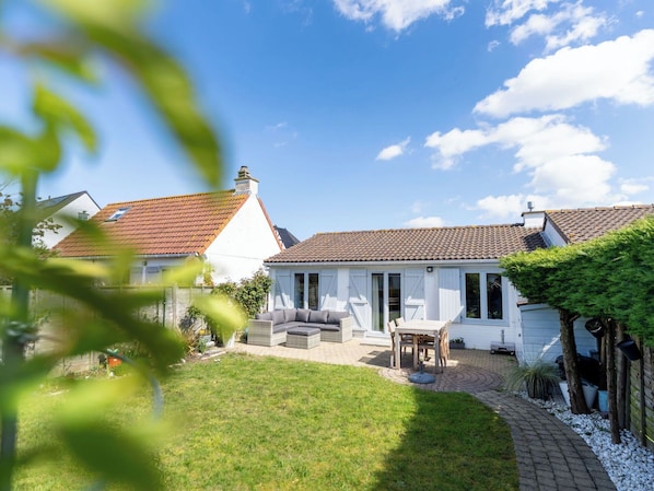A house with a tiled roof, a covered patio, and a lawn.