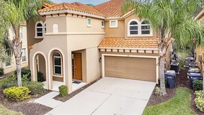 A two-story house with a beige facade, a tiled roof, and a garage.