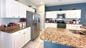 A modern kitchen with white cabinets, stainless steel appliances, and granite countertops.