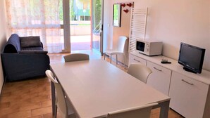 Un espace de vie compact comprenant un canapé, une table à manger, un téléviseur et un four à micro-ondes.