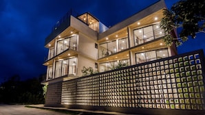 A modern multi-story building with balconies and large windows, surrounded by a decorative fence.