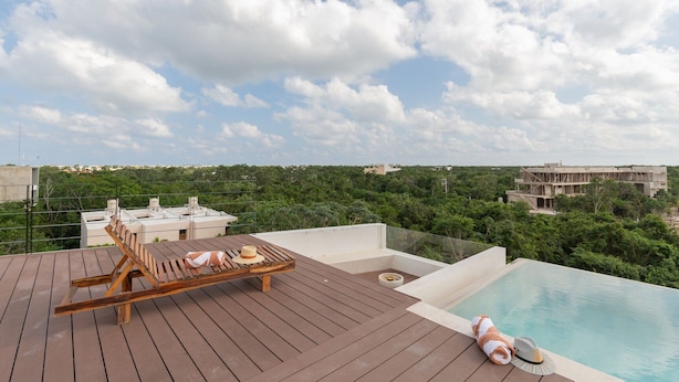 A rooftop pool area with wooden loungers and a small pool.