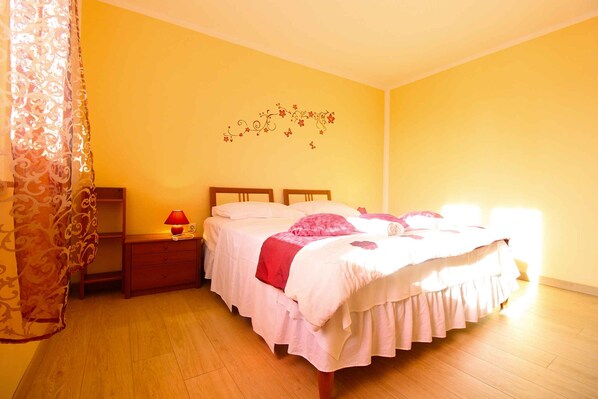 A bedroom with two beds, a nightstand with a lamp, a dresser, and a wall decoration.