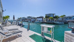 Un port de plaisance avec des bateaux amarrés, un espace piscine avec des chaises longues et une vue dégagée sur l’eau.