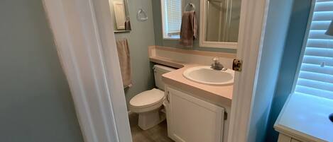 A compact bathroom with a toilet, sink, and mirror.